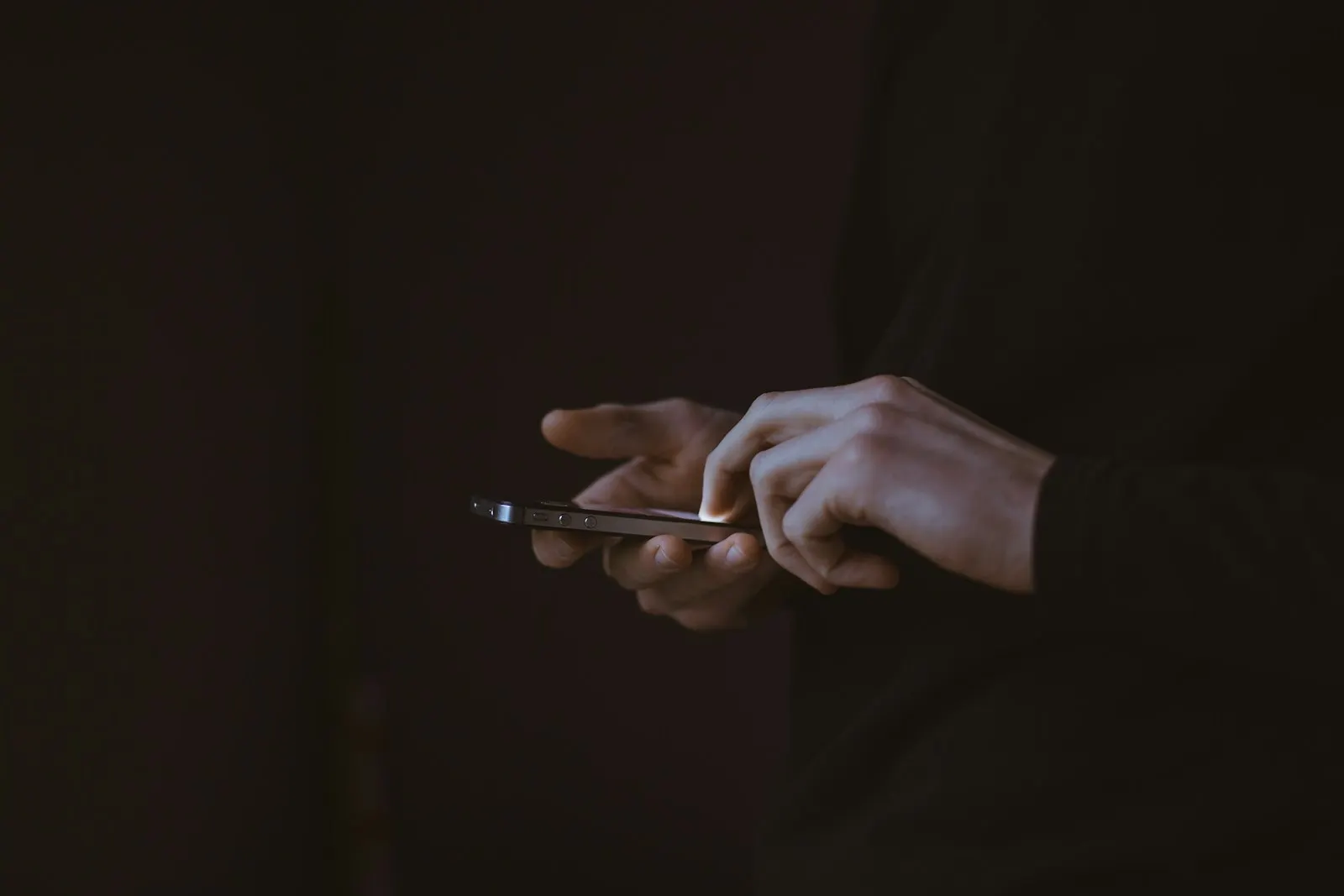 Hands holding a lit phone screen in a dark room